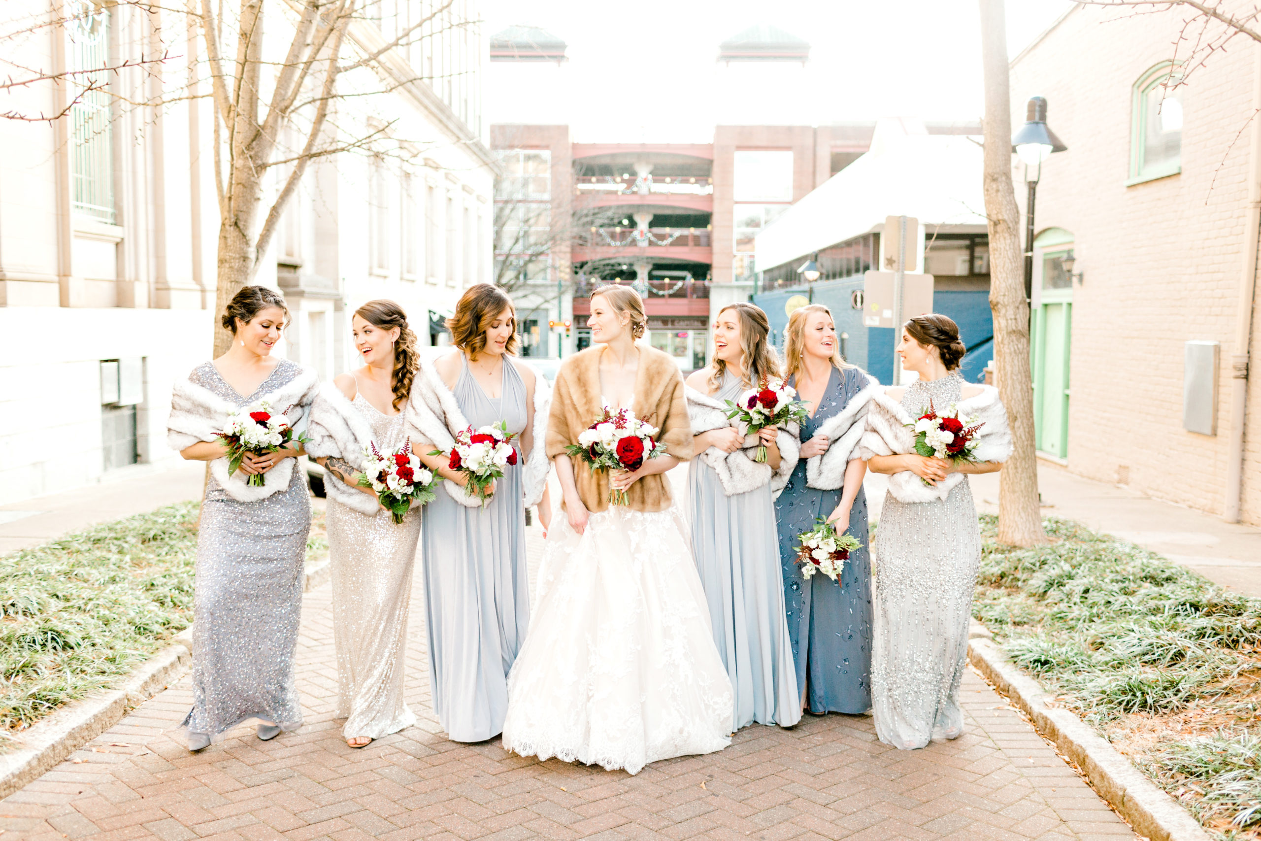 Bride and bridesmaids walking together with blue dresses and fur shawls